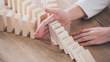 A hand preventing dominos from falling