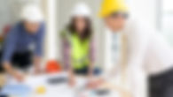 Three people in hard hats looking at construction plans