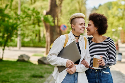 Two young woman walking arm-in-arm on campus