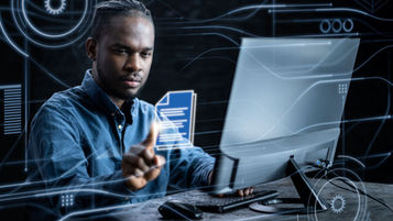 A man at a desktop computer with images projected in the space around him