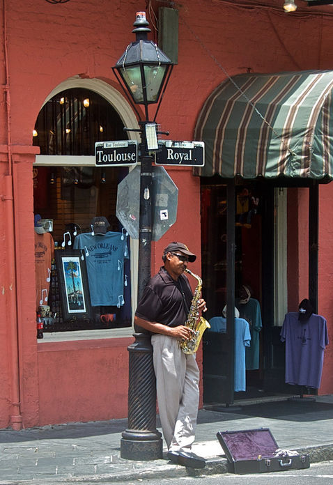 A man leaning on a lamppost in the French Quarter of New Orleans