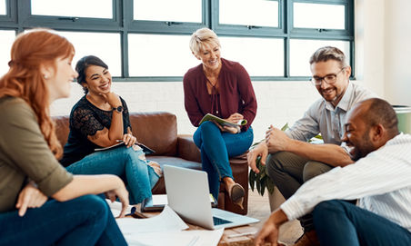 A team of diverse people seated around a laptop