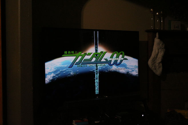 On the TV screen, the Gundam 00 title card displays. Whoever is sitting on the couch is getting ready to watch. Photo credit: Jacob Harris