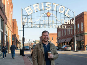 Business owner holding a cup of coffee in front of the Bristol State Street sign