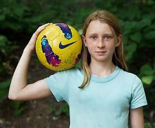 girl with soccer ball on shoulder