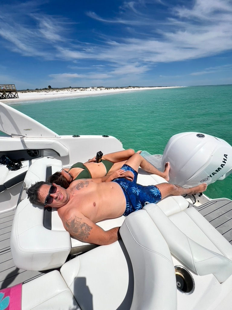 Couple relaxing on a boat during a Shell Island Private Dolphin & snorkeling trip in Panama City Beach.