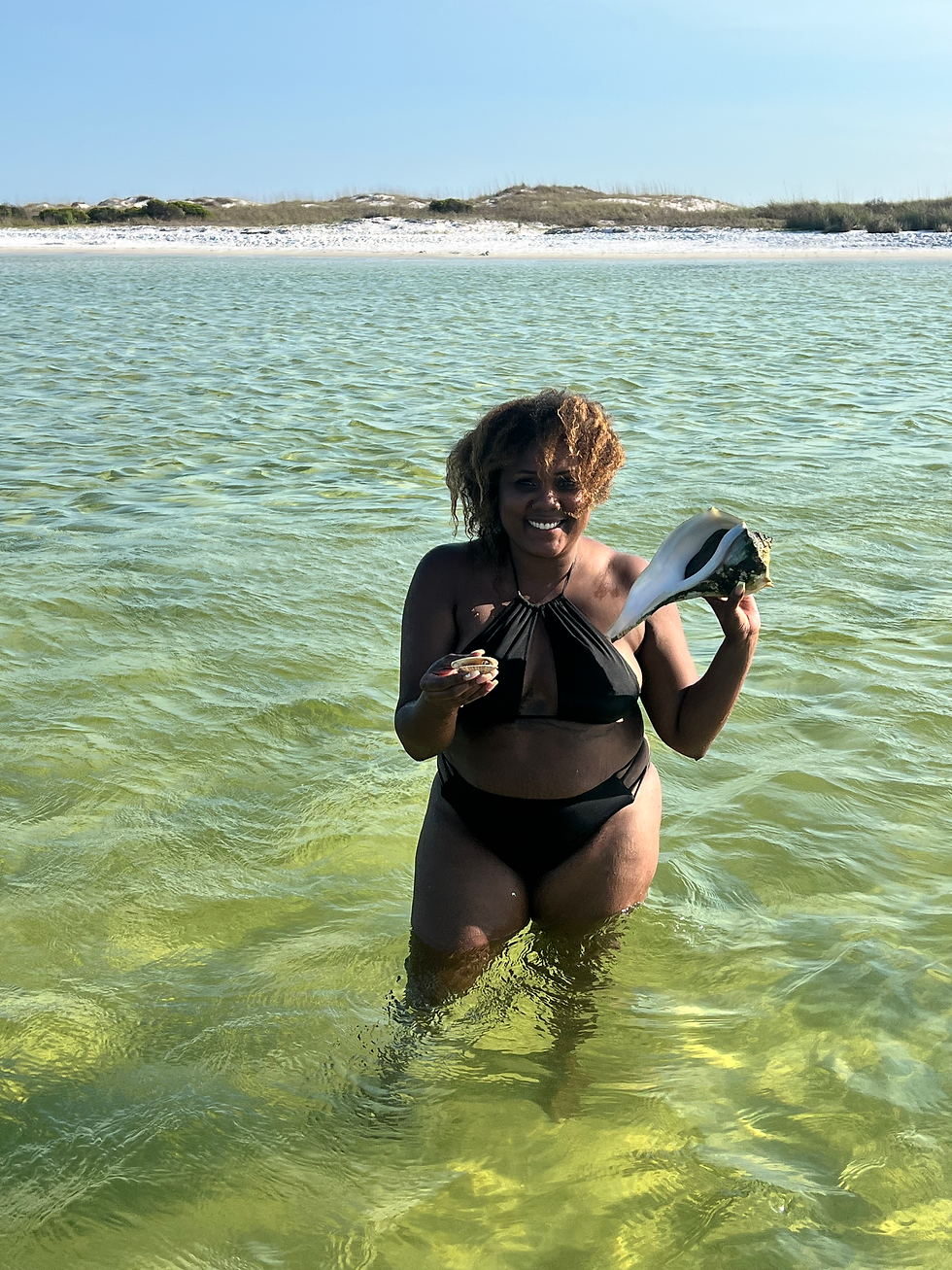 Woman holding a large shell in Panama City Beach water.