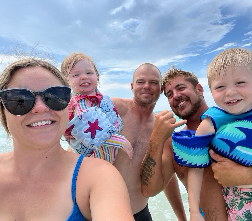 Smiling family with two young children at the beach