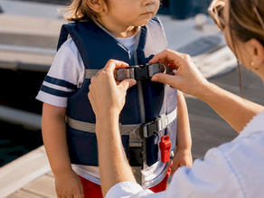 Parent securing toddler’s properly fitted life jacket