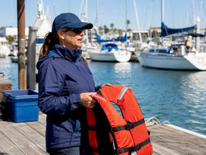 Instructor holding USCG-approved life jacket on boat deck