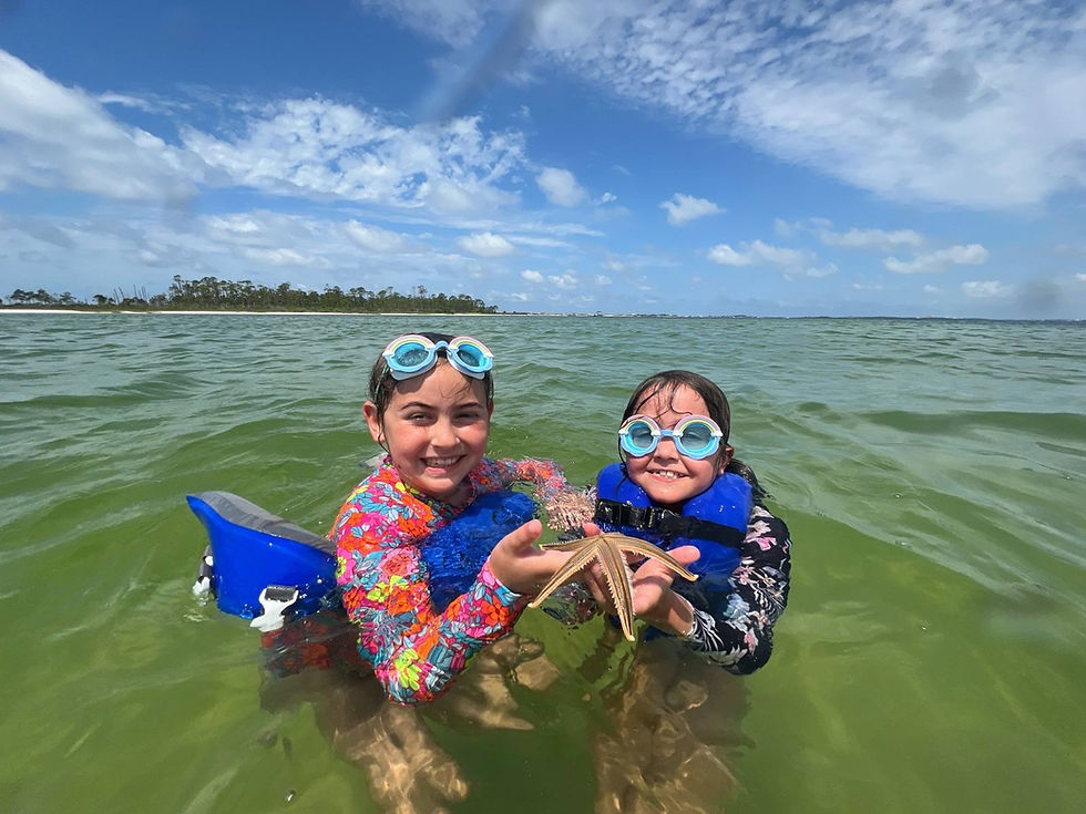 Smiling girls in goggles holding a starfish in clear ocean