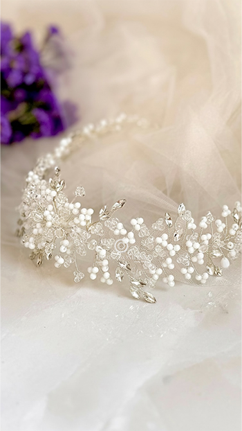 Tiara Magnolia con racimos de vidrios blancos y transparentes y ramas de cristales sobre fondo claro.
