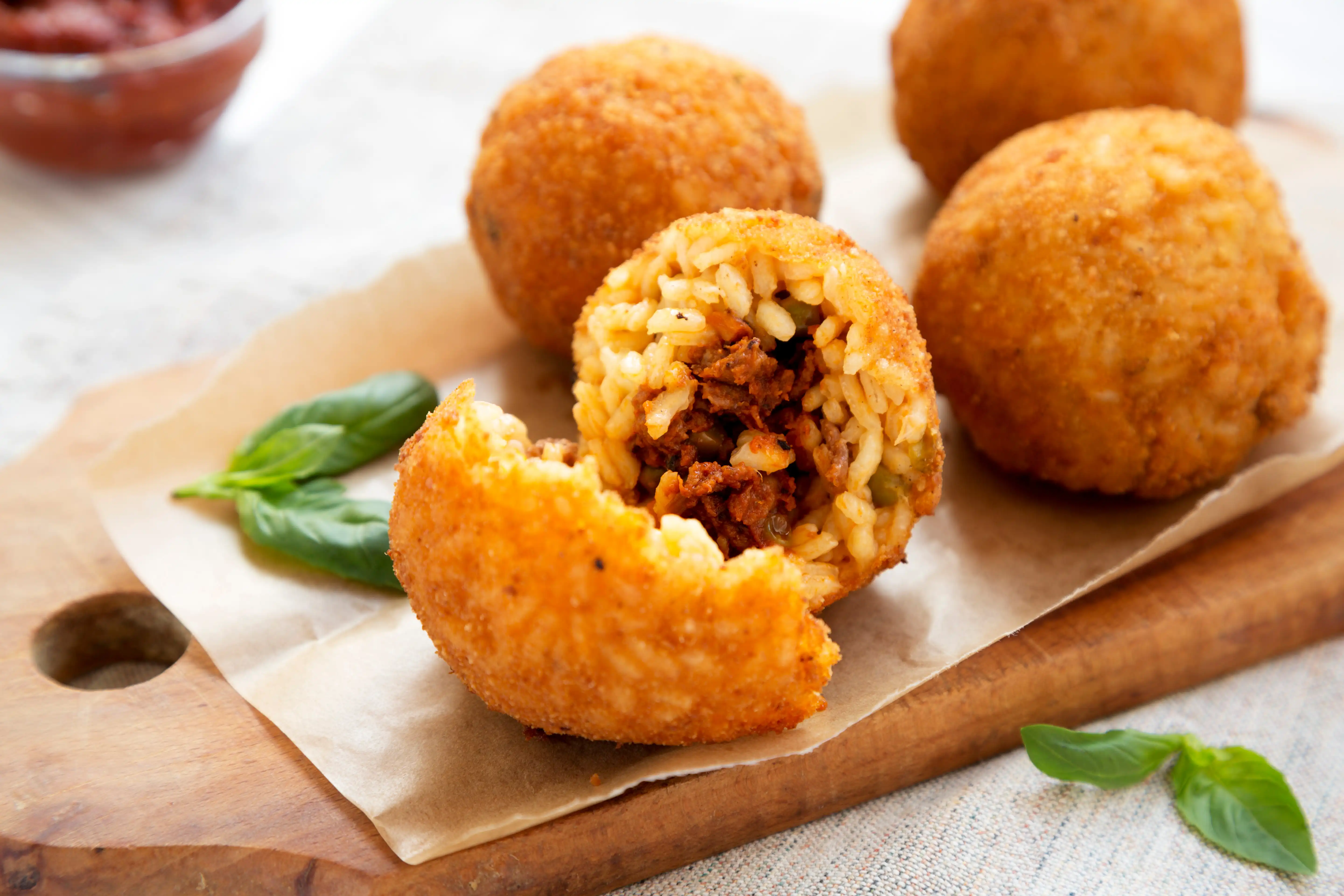 Homemade fried Arancini with basil and Marinara on a white wooden background