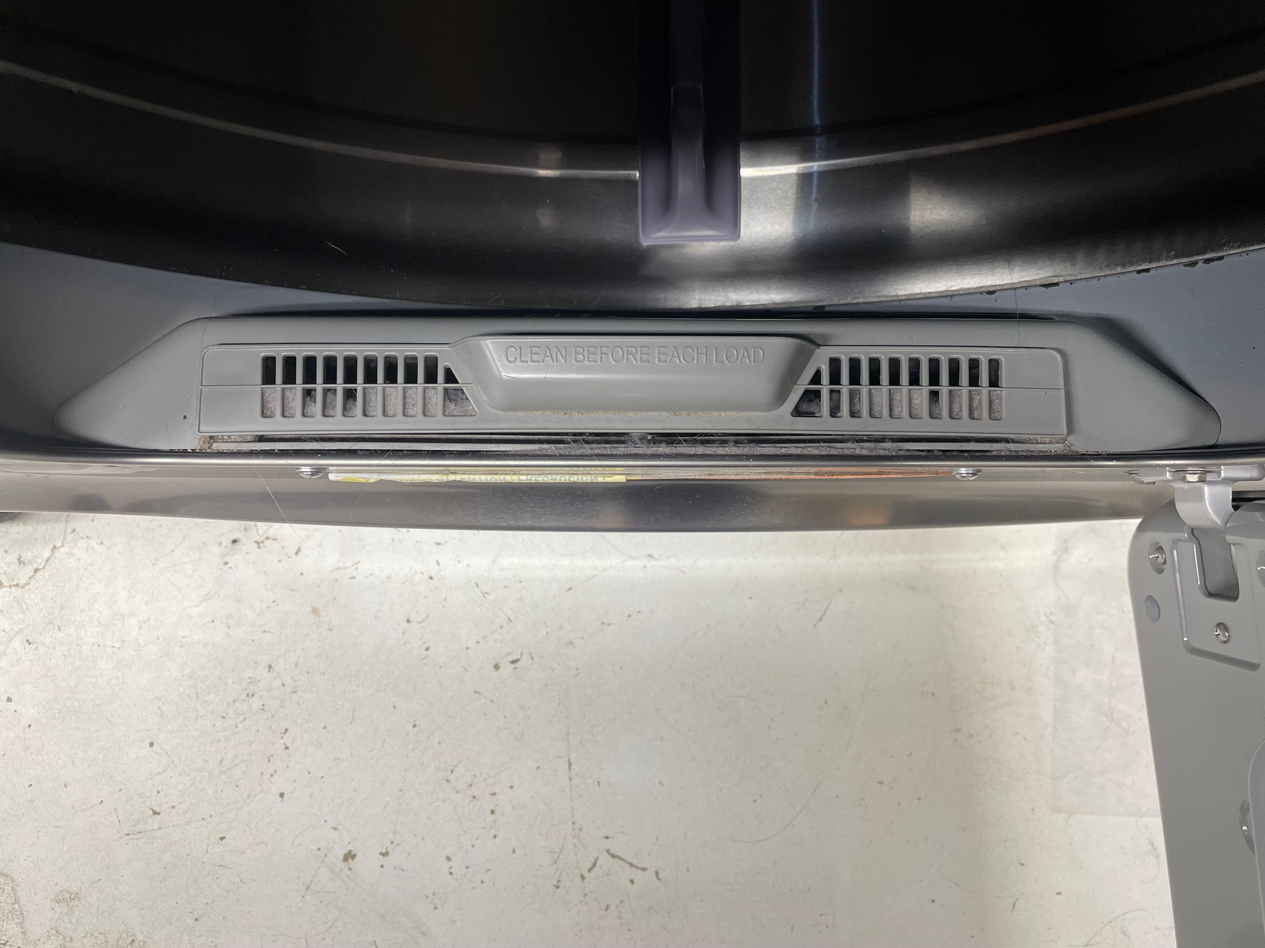 Photo of a dryer's lint trap slotted into place at the bottom of the dryer.