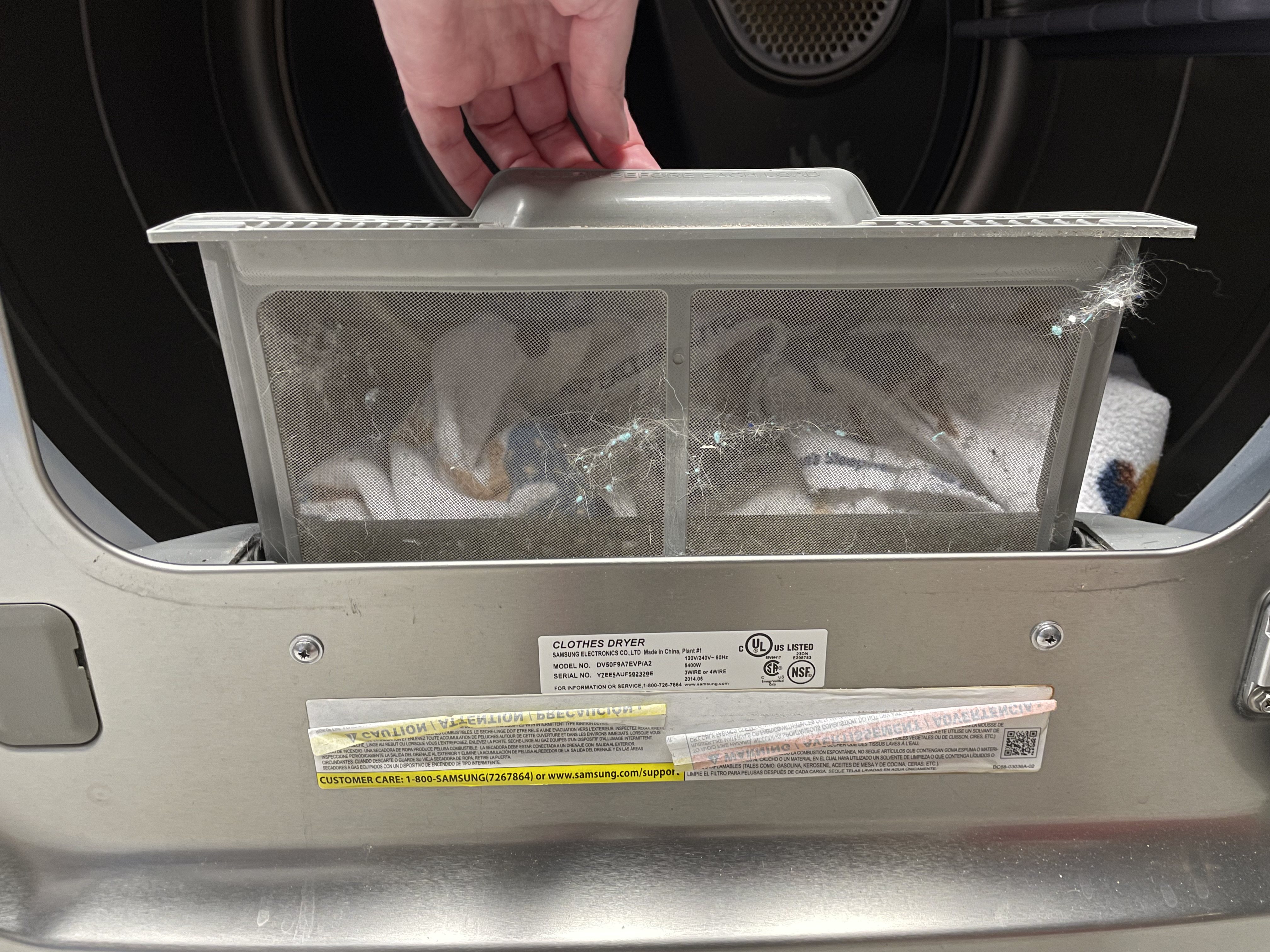 Photo of a lint trap being removed from a dryer.