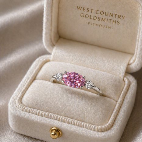 an east west pink sapphire and diamond engagement ring in a ring box