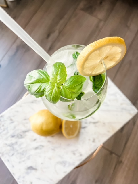 A lemon basil mojito with a slice of lemon and a sprig of mint as garnish.