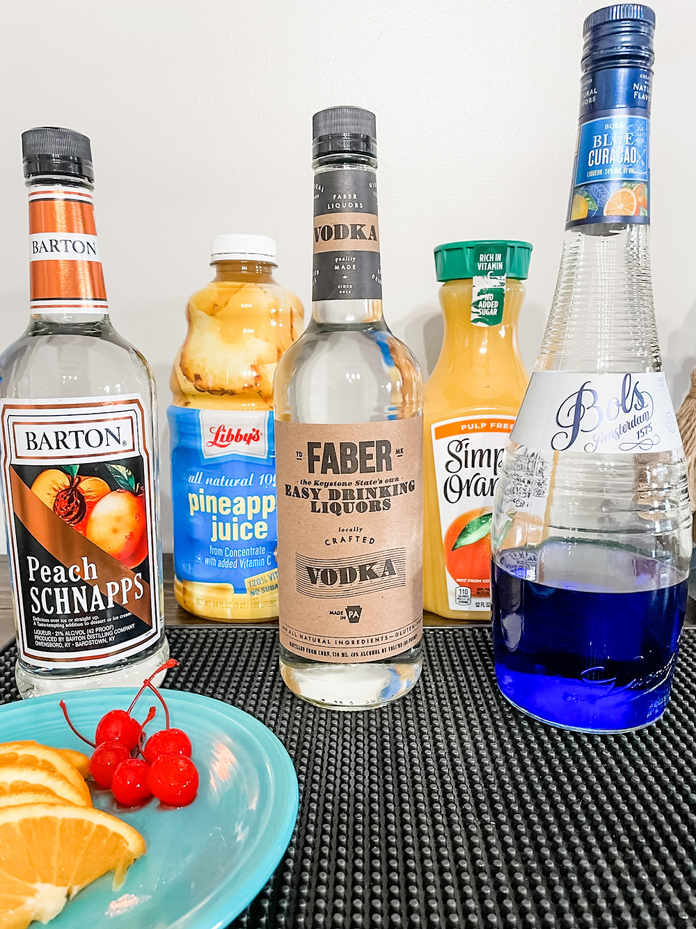 The ingredients for the Fuzzy Leprechaun, Peach schnapps, pineapple juice, Faber Vodka, Orange juice and Blue Curacao.