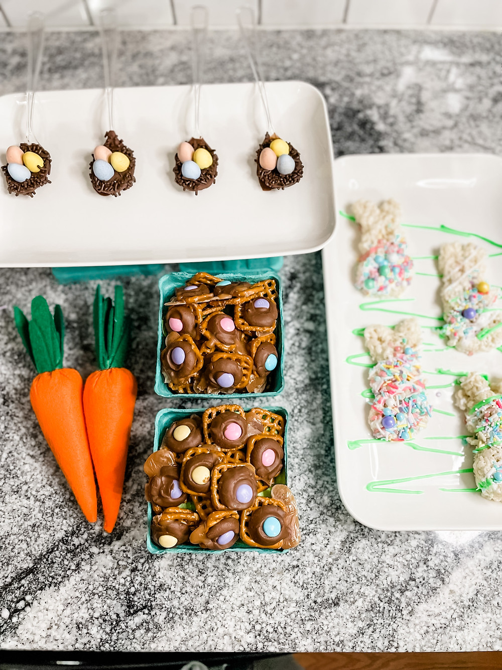 Kid friendly Easter Treats displayed on a counter, Chocolate birds nests, bunny rice krispy treats and chocolate caramel pretzel bites