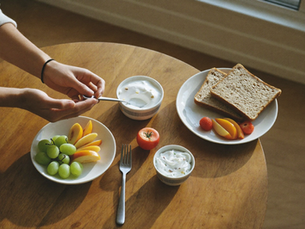 A simple post-workout meal of yogurt, fresh fruit, and whole-grain toast arranged on a wooden kitchen table.