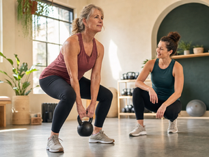 Two women perform kettlebell squats together indoors as part of a simple strength routine.