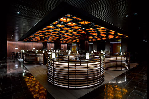 Dark restaurant with round stools and orange squares ceiling