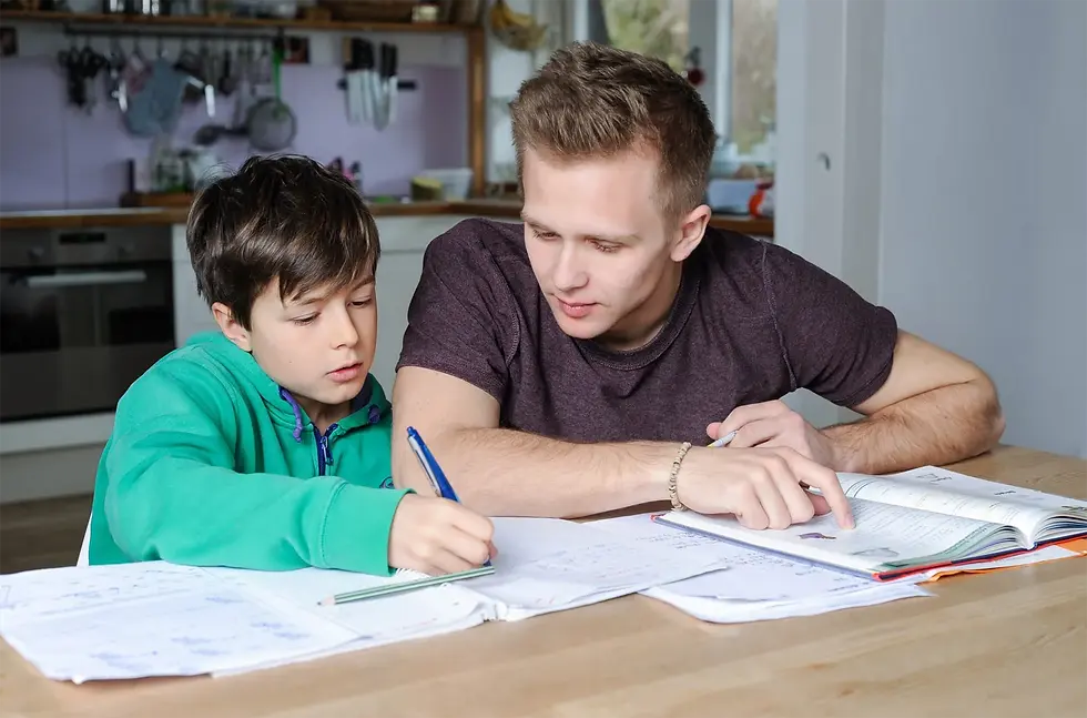 Vater sitzt gestresst neben seinem Kind beim Hausaufgaben machen – Tipps bei Lernstress und familiärer Erschöpfung