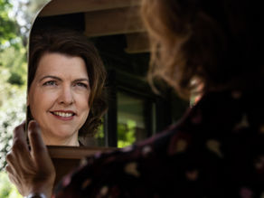 Vrouw die in spiegel kijkt als metafoor voor synchroniciteit als spiegel van het leven.