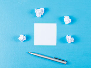 photographie-feuille-papier-stylo-boules-papier-froisse-fond-bleu