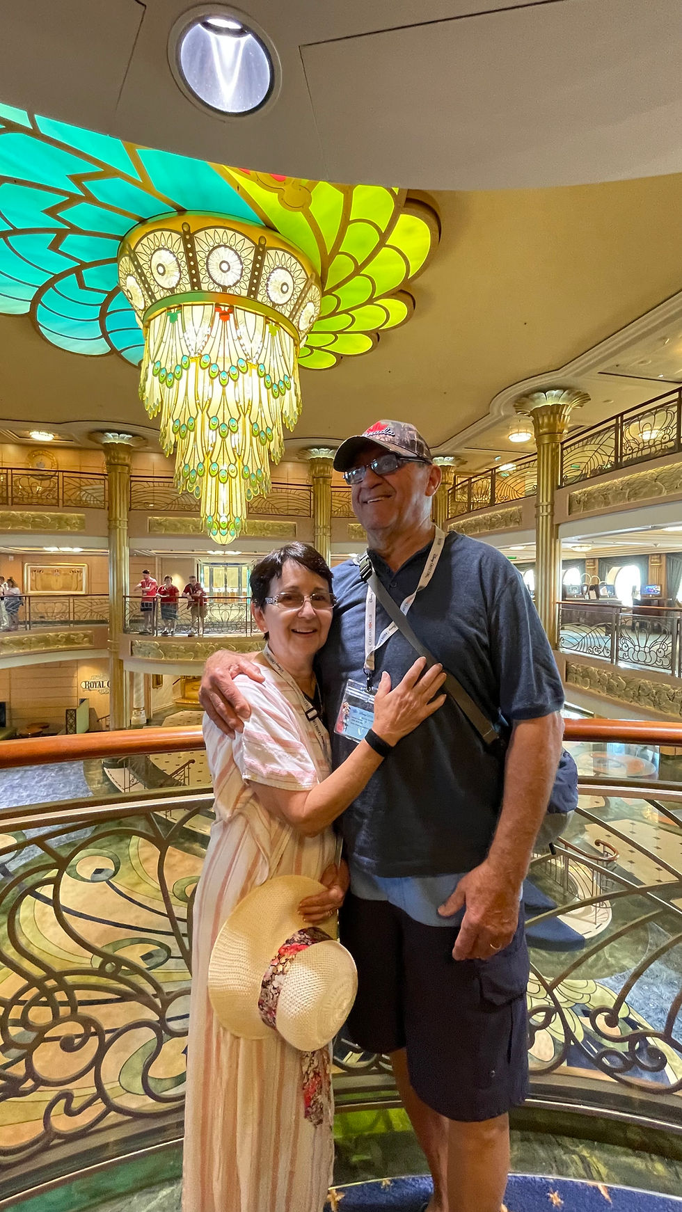 Couple posing together beneath a colourful chandelier in the atrium of a Disney cruise ship.