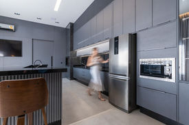 Cozinha Moderna planejada cinza com armário modulado e Ilha Central com eletrodomésticos embutidos.