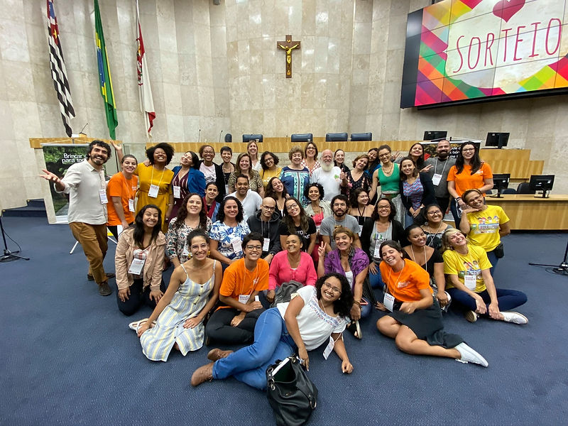Um grupo de aproximadamente 60 pessoas sorrindo no evento presencial do Encontro de Agentes do Brincar.