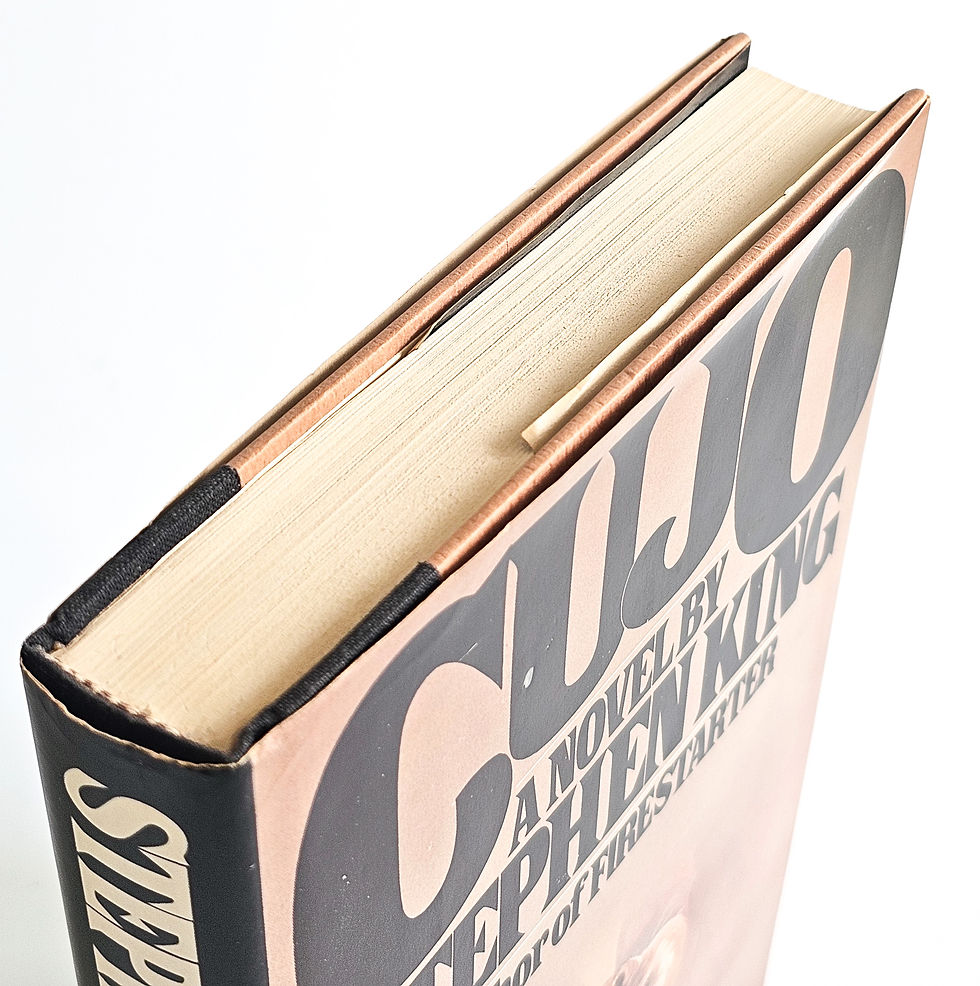Head and top edge of Cujo, Viking Press 1981 first edition, showing the black cloth spine and jacket edges
