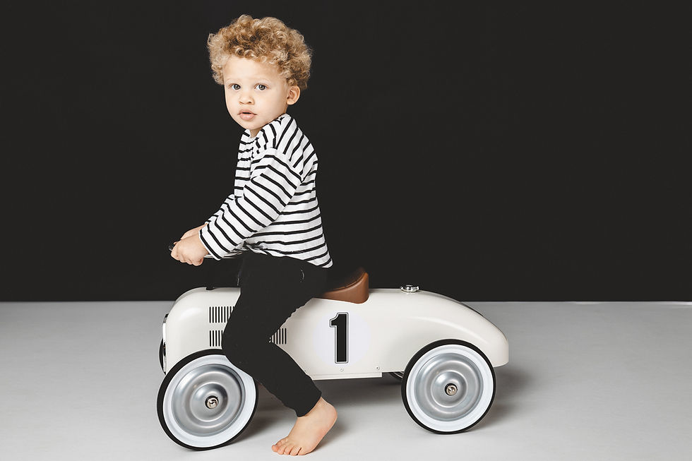 Foto von einem Jungen auf einem nostalgischen Bobbycar