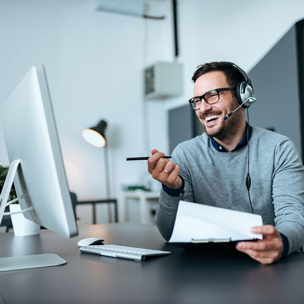 man wearing a headset witting at desk holds a clipboard
