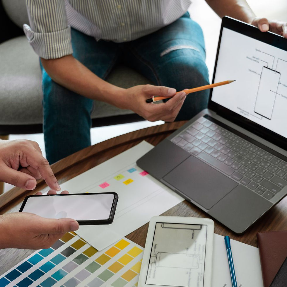 Close-up of a desk covered with color swatches, someone pointing to a design on a laptop