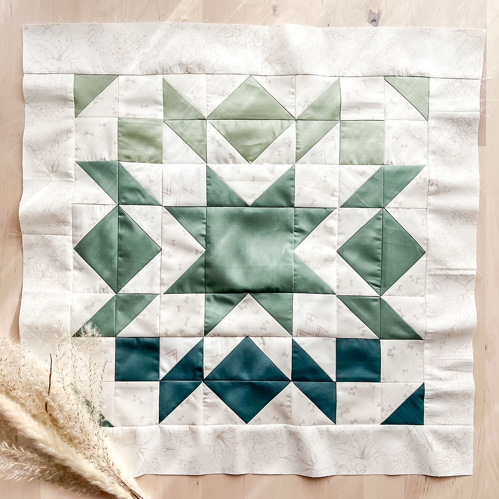 Cream and green star quilt block on a wood table.