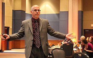 Joe Serio with arms open in a conference room