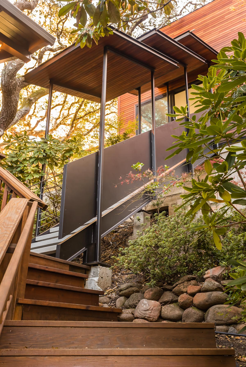 Modern wooden staircase with black steel canopy and railings