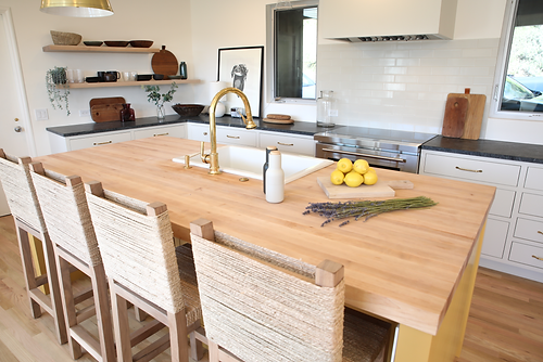 Modern kitchen with wood island, gold faucet, and woven stools