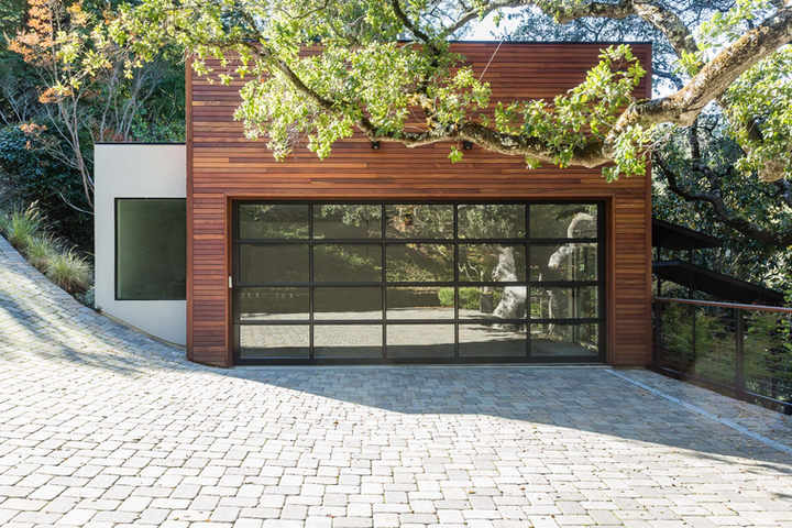 Modern glass panel garage door on a wood-sided home.