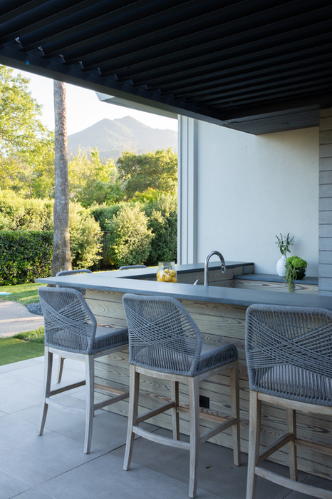 Modern outdoor bar with woven stools and mountain views