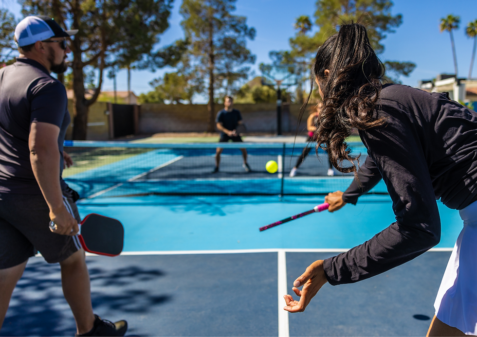 A doubles game of pickleball being played outside.
