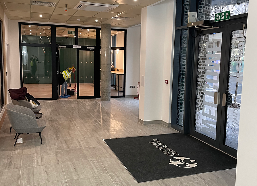 Builders’ clean operative preparing the entrance to new build residential flats for final presentation