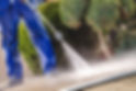 A man jetwashing a driveway outside someones house