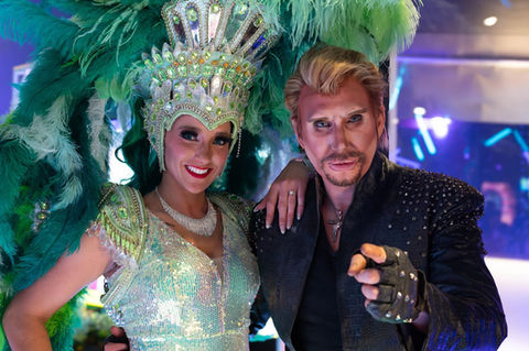 Johnny Hallyday et une danseuse en costume à plumes vertes