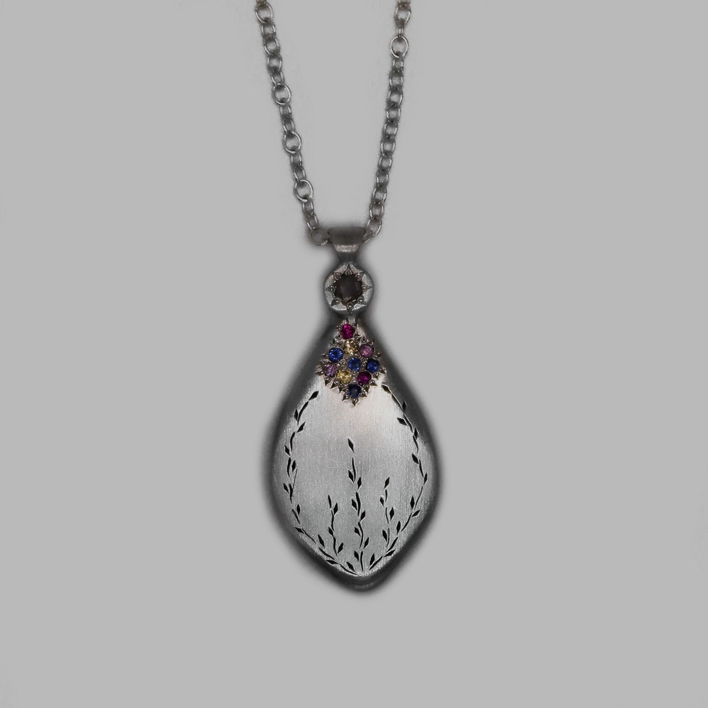a silver necklace with a leaf shaped pendant on a chain