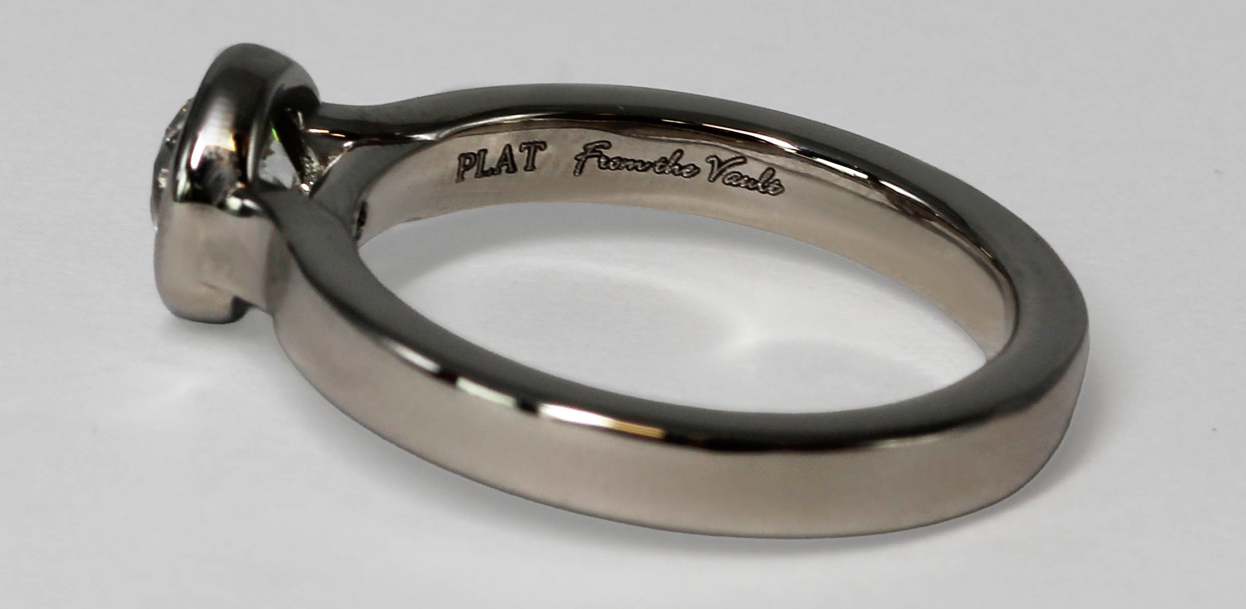 Polished silver ring on white background, engraved PLAT From the Vault visible on inner band, product shot