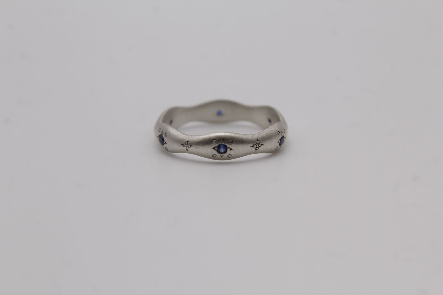 a silver ring with blue sapphires on a white surface