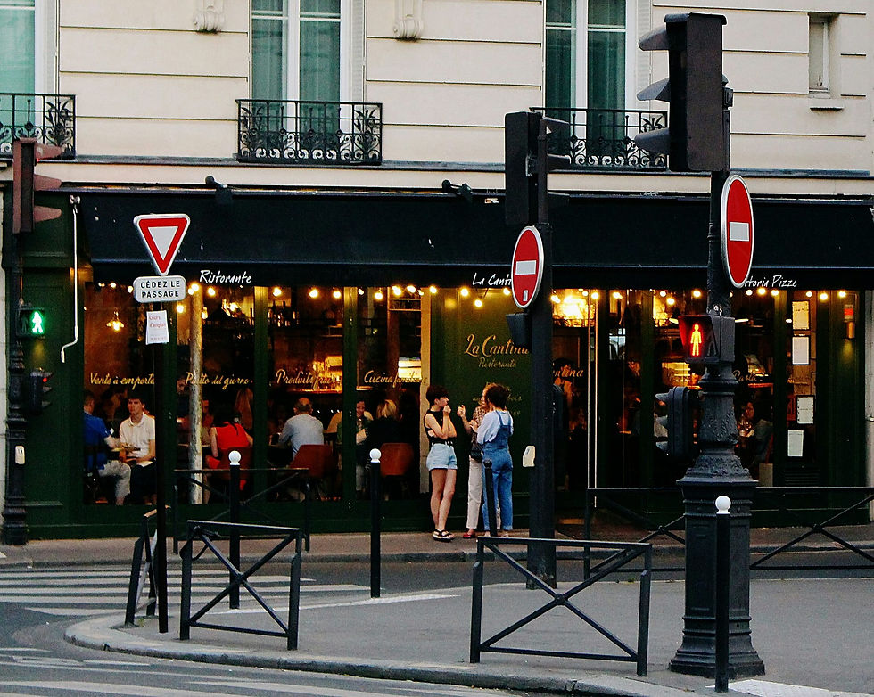 People gather in front of a bustling Parisian restaurant, enjoying an evening in the vibrant city atmosphere.